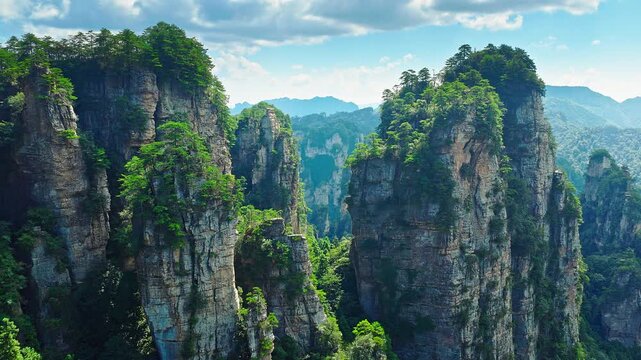 Aerial shot of majestic quartz-sandstone pillars and mountains with lush green forest vegetation in a national park in Hunan, China.