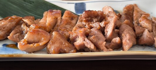 Sliced grilled pork neck on a white plate