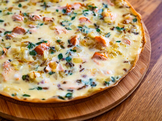 Frittata - scrambled eggs with roasted salmon bites, fried onion and fresh thyme on wooden table	