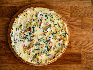 Frittata - scrambled eggs with roasted salmon bites, fried onion and fresh thyme on wooden table	