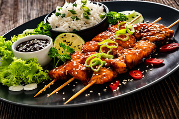 Fried teriyaki salmon skewers with white rice on wooden table