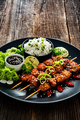 Fried teriyaki salmon skewers with white rice on wooden table