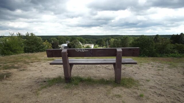 Time lapse video of a wooden park bench as sunlight shifts over the forested hills near Kr&auml;henberg in Caputh, Brandenburg.