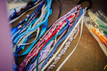 Colorful handmade hippie-style braided hair accessories and ribbons laid on a table, showcasing bohemian craftsmanship and vibrant textures.