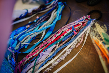 Colorful handmade hippie-style braided hair accessories and ribbons laid on a table, showcasing bohemian craftsmanship and vibrant textures.