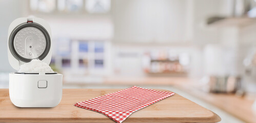 White rice cooker with fresh steamed rice on wooden kitchen table
