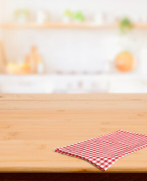 Wooden surface with checkered cloth and blurred home kitchen interior