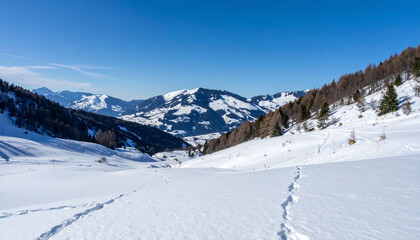 Obraz premium the image captures a serene winter landscape dominated by snow covered mountains under a bright blue sky