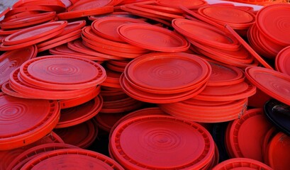 A pile of orange plastic 5 gallon bucket lids. © Ohso Photos