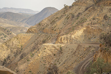 Remote cliffside path snaking through Moroccan mountains, blending into the arid landscape with dramatic elevation and rocky textures