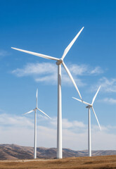 Fototapeta premium Wind Power Plant by the Riverside, Encircled by Lush Green Grass, with Distant Mountains and a Blue Sky. Captures the Vast, Harmonious Blend of Nature and Modern Technology.