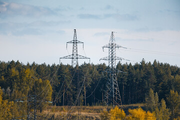 High voltage electricity transmission pylon against autumn forest on a background