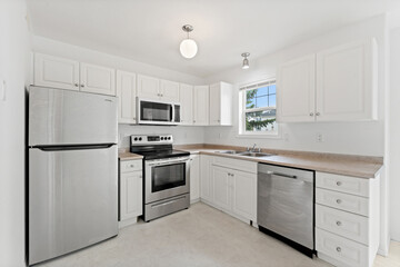 Fototapeta premium Clean and well-lit kitchen with stainless steel appliances and white cabinets