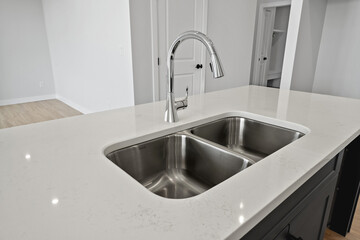 Stainless steel sink with a silver faucet sits on a white countertop