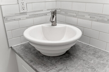 White sink with a silver faucet sits on a grey countertop
