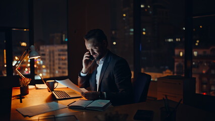 Evening businessman calling mobile phone consulting in evening office closeup