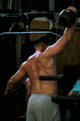 Naklejka premium Homme musclé faisant un exercice avec kettlebell en salle de sport