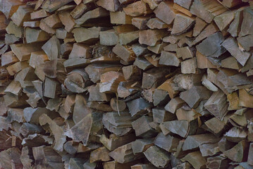A dense wall of stacked firewood in natural shades of brown and gray, creating a rich, rustic texture and pattern perfect for backgrounds and cozy themes.