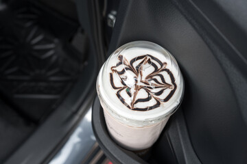 An iced coffee drink placed in a cup holder inside a car. Close up.