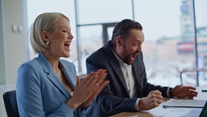 Amazed businesspeople rejoicing victory looking laptop cityscape office closeup