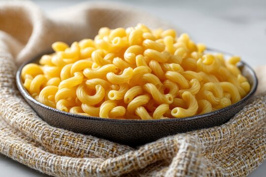 A bowl filled with cavatappi pasta sits on a folded cloth
