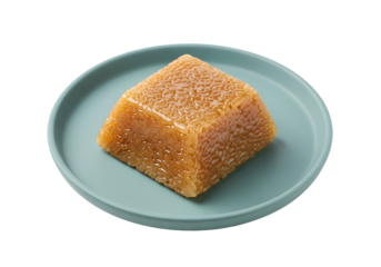 A square block of golden-hued cooked rice sits on a light teal plate against a black background.