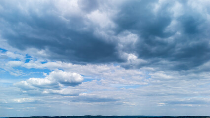 Obraz premium Vast sky filled with dramatic clouds casting shadows over the landscape below, showcasing a serene atmosphere perfect for nature photography or weather-related themes.