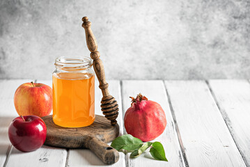 Apples, pomegranate and jar of honey on a white wooden rustic table. Holiday Rosh Hashanah....