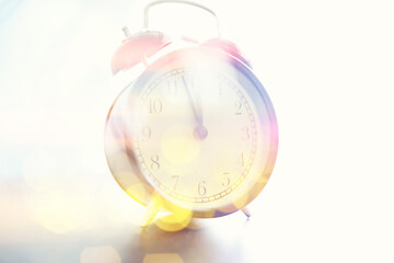 Background with a clock on the table and bokeh in pastel rainbow colors. Time for rest and travel.