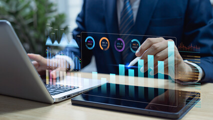 Businessman analyzing data on laptop and tablet with performance dashboard representing business report, economic growth charts market research KPIs and strategic planning corporate decision making. © Father_Studio