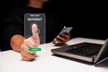 A person using biometric authentication for a payment on a smartphone while sitting at a desk with a laptop.