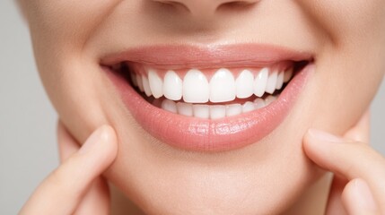 Obraz premium A person smiles widely, revealing well-maintained teeth and smooth lips. The background is neutral, allowing the bright smile to be the focal point. Natural light enhances the cheerful expression.