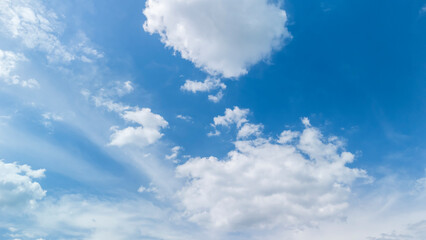 Bright blue sky filled with white clouds, creating a serene and peaceful atmosphere. Ideal for backgrounds, nature themes, and weather-related content.