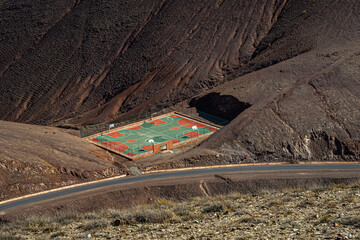 Colorful basketball court in Morocco Atlas Mountains built in rocky desert valley surrounded by...