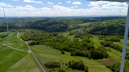 Aerial view of lush green hills and valleys with wind turbines, showcasing the beauty of nature and...