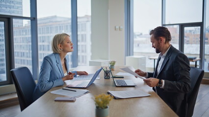 Focused employees reviewing paperwork at workspace closeup. Smiling accountants