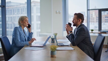 Busy executives using mobile phones in boardroom. Partners exchanging documents