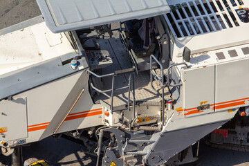 This detailed, high-angle shot of a road milling machine's operator platform and control panel is perfect for a designer needing visuals of heavy industrial equipment, engineering, or urban infrastruc