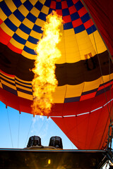 Obraz premium A vibrant hot air balloon with flames rising from the burner, creating a stunning contrast against the colorful canopy.
