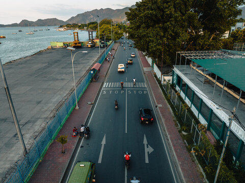 Aerial view of a bustling road marked with crosswalks and directional arrows, bordered by the sea and lush greenery, Dili, D&Atilde;&shy;li, Timor-Leste.