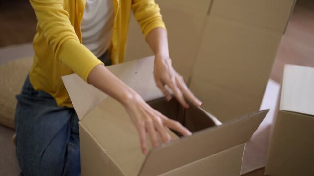 Adult hands meticulously preparing cardboard moving box sealing securely for relocation home apartment office transport packing services