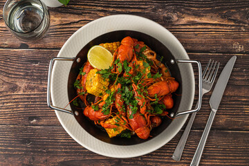 Cooked crayfish with corn and herbs in a serving pan