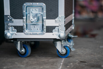 Protective transport case with rolling wheels on concrete floor, secure storage solution used for equipment, events, music gear or stage production with mobility and safety features