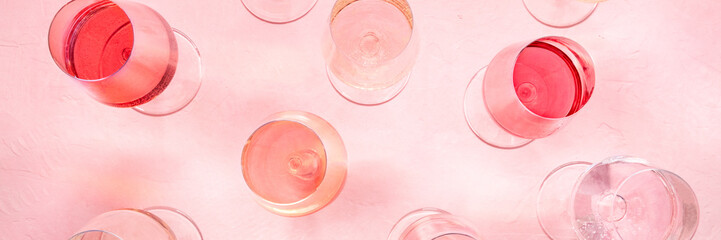 Rose wine panorama, overhead flat lay shot, different hues and tints, on a pink background, many wine glasses, panoramic banner
