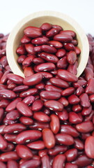 Close-up of red kidney beans spilling from a wooden bowl, representing nutritious legumes, healthy food ingredients, and plant-based protein sources.