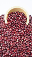 Adzuki beans spilling from wooden bowl on white background