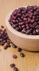 Adzuki beans in wooden bowl on wooden surface