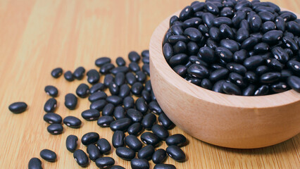 Black beans in wooden bowl on wooden surface