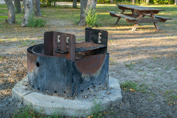 fire ring with barbecue grill and weathered wooden picnic table in Whitetail Campground in Nebraska National Forest near Halsey