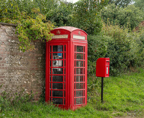 red telephone box complete with phone beside a red post box